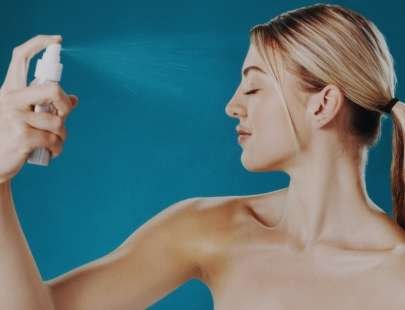 donna che applica spray purificante viso al tea tree